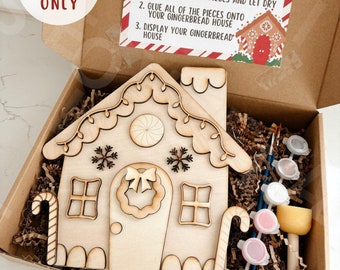 May include: A gingerbread house paint kit in a brown cardboard box. The kit includes a wooden gingerbread house, paint, brushes, and a sponge. The box has a label that says "Gingerbread House Paint Kit" and includes instructions for painting and assembling the house.