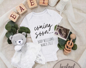 May include: A white onesie with the text "coming soon... Baby Williams March 2022" on it.  The onesie is surrounded by a white blanket, wooden blocks spelling "BABY", a gray teddy bear, a pair of white booties, and a wooden rattle.  The image also includes a sonogram photo and a green leafy plant.