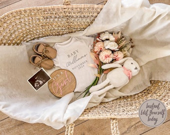 Op de afbeelding: Een rieten mand gevuld met babyartikelen, waaronder een wit rompertje met de tekst "Baby Williams November 2024", een houten bord met de tekst "It's a Girl" in roze letters, een paar bruine slofjes, een boeket roze en witte bloemen en een gehaakt knuffeldier.