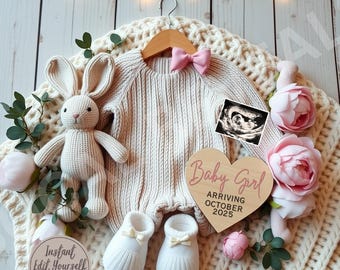 Op de afbeelding: Een houten hartvormig bord met de tekst "Baby Girl Arriving October 2025" in roze letters. Het bord is omringd door een gebreide deken, een gehaakt konijn en een paar witte baby-schoentjes.