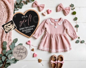 Op de afbeelding: Een zwart hartvormig schoolbord met de tekst "It's a girl! Baby Williams November 2024". Een roze babyjurk met kant, een paar bruine schoenen met roze strikken en een kleine echografiefoto zijn ook op de foto te zien.