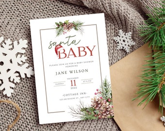 May include: A white baby shower invitation with a green and red watercolor illustration of pine branches, pine cones, and holly berries. The text reads "santa baby" in green and red script. The invitation includes the date, time, and location of the shower.