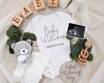 May include: A white onesie with the text "Baby Williams" and "March 2023" printed on it.  The onesie is surrounded by wooden blocks spelling "BABY", a gray teddy bear, a pair of white booties, a wooden rattle, and a framed ultrasound image.
