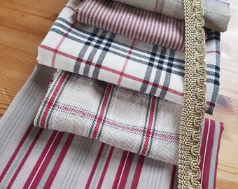 Pode incluir: Um conjunto de seis amostras de tecido em vários padrões de xadrez e listras com cores vermelho, branco e cinza. Uma guarnição dourada é visível no lado direito da imagem.