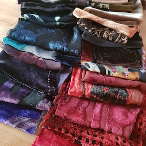 Può includere: Una collezione di campioni di tessuto di velluto in vari colori e motivi. I campioni includono sfumature di blu, viola, rosso e oro, con trame che vanno da tinta unita a fantasia. Alcuni tessuti presentano disegni floreali.