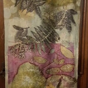 Peut inclure: Une &eacute;charpe en soie blanche avec un imprim&eacute; botanique repr&eacute;sentant des feuilles et des fleurs dans des tons de vert, marron et rose.