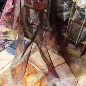 Puede incluir: Una tela transparente con un diseño de acuarela en tonos naranja, rojo, morado y blanco. La tela parece estar en capas, creando profundidad y dimensión. El efecto general es artístico y etéreo.