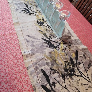 Può includere: Un runner da tavolo in lino bianco con un design astratto in nero e oro. Il runner è decorato con un candelabro a sette bracci in vetro.