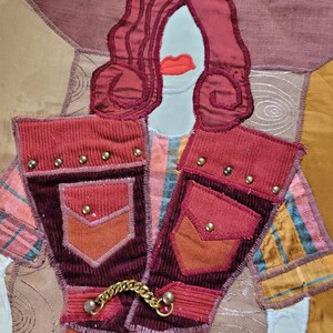 以下が含まれることがあります： 赤毛のスタイリッシュな人物が、ポケットと金色のチェーンが付いた赤と茶色のコーデュロイジャケットを着ているパッチワークキルト。人物は赤い唇をしていて、茶色、ベージュ、ピンクの様々な生地の背景に置かれています。