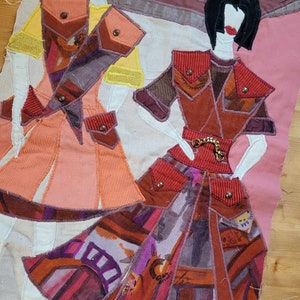 以下が含まれることがあります： 黒い髪と赤い唇をした布製のドール2体が、カラフルなパッチワークの衣装を着ています。ドールは白い背景に立っており、黒い文字で「VSEKTÖR」と書かれています。