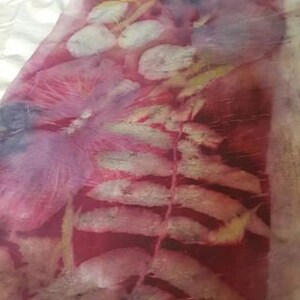 Peut inclure: Un gros plan sur un tissu avec un imprim&eacute; botanique. Le tissu est de couleur rouge fonc&eacute; avec un motif de feuille de foug&egrave;re dans une nuance plus claire de rouge et de blanc. L'arri&egrave;re-plan est de couleur cr&egrave;me clair.