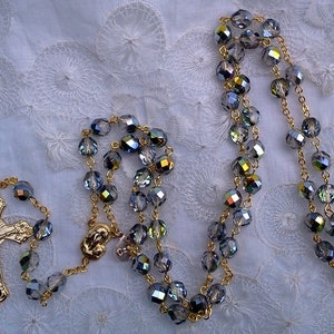 May include: A gold rosary with a gold crucifix and blue iridescent glass beads.