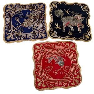 May include: Three square decorative cushions in navy blue, black, and red. Each cushion features gold embroidered designs, including fish and mythical creatures. The cushions have scalloped edges and are suitable for home decor.