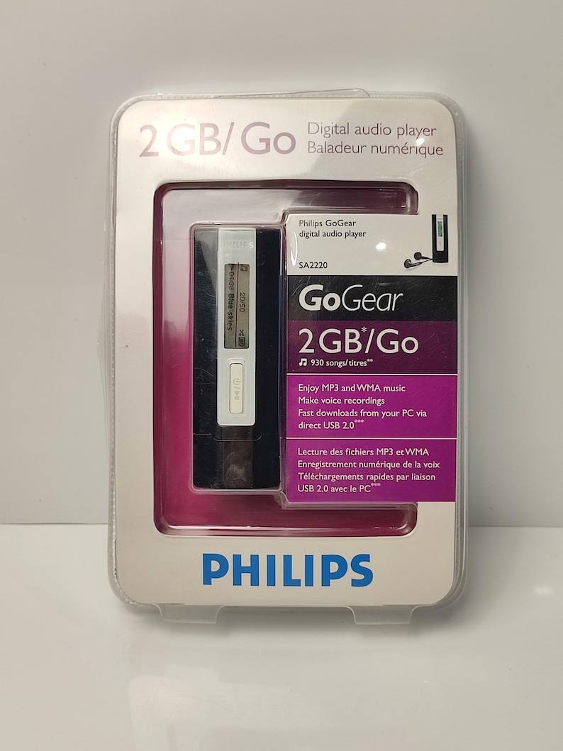 Pu&ograve; includere: Un lettore audio digitale Philips GoGear nella sua confezione originale. Il lettore &egrave; bianco e nero, con un piccolo schermo e pulsanti. La confezione &egrave; in plastica trasparente con un inserto rosa e bianco e include il testo "2 GB/Go".