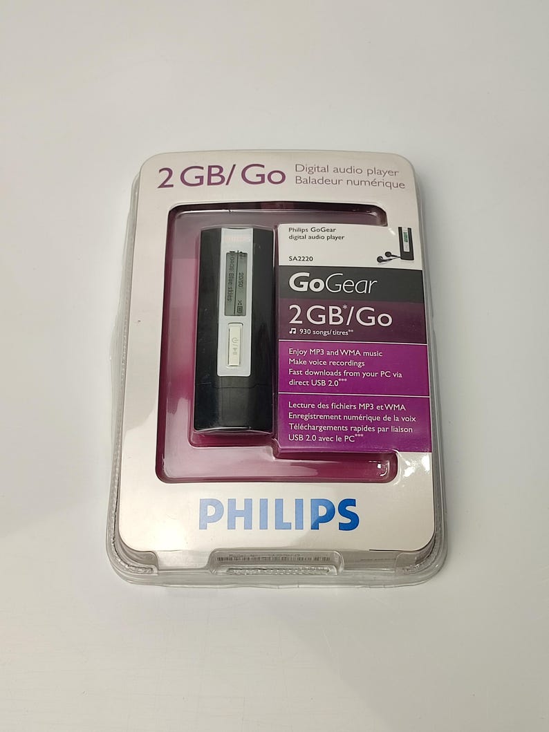Pu&ograve; includere: Un lettore audio digitale Philips GoGear nella sua confezione originale. Il lettore &egrave; nero e argento, con un piccolo schermo. La confezione indica una capacit&agrave; di 2 GB e presenta il logo Philips.