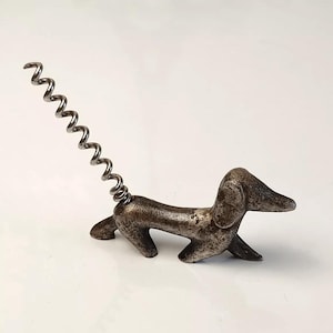 Può includere: Un cavatappi in metallo argentato a forma di bassotto con una coda a molla.