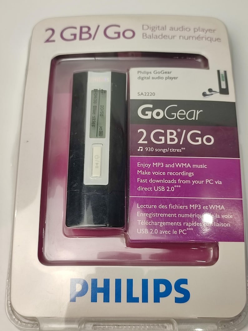 Pu&ograve; includere: Un lettore audio digitale Philips GoGear nella sua confezione originale. Il lettore nero ha un piccolo schermo che mostra le informazioni sulla canzone. La confezione include il testo "2 GB/Go" e "930 canzoni/titoli".