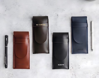 May include: Four rectangular leather pen cases in brown, dark brown, black, and navy blue. Each case features a flap closure, visible stitching, and personalized text including M. CARTER, IGHTW, and EMILY. The cases are arranged on a white surface.
