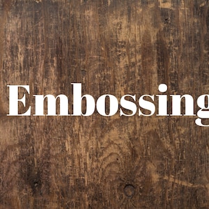 Puede incluir: La palabra "Embossing" en letras blancas en negrita sobre un fondo de madera marrón.