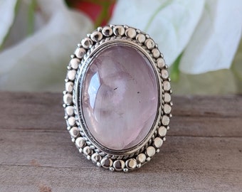May include: A silver ring with a large oval-shaped pink gemstone set in a beaded bezel.
