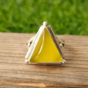 May include: A silver ring with a triangular yellow gemstone set in a silver frame.