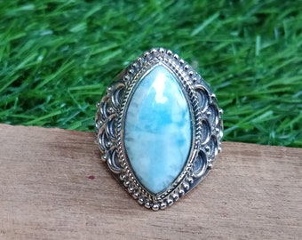 May include: A silver ring with a large, oval-shaped blue and white gemstone set in a decorative filigree design.