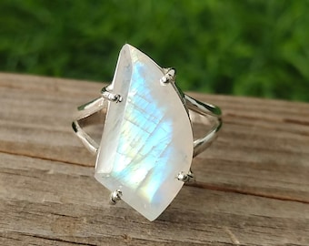 May include: A silver ring featuring a large, iridescent moonstone set in a delicate, openwork design.