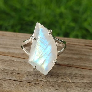 May include: A silver ring with a large, iridescent moonstone set in a delicate, open-work design.