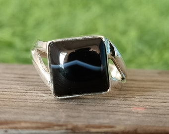 May include: A silver ring with a square black agate gemstone. The ring has a unique design with a split band.