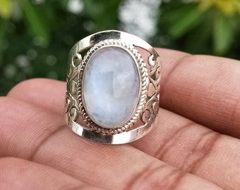May include: A silver ring with an oval-shaped moonstone set in a decorative filigree design.