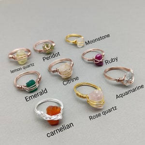 May include: Ten different wire-wrapped rings with various gemstones, including citrine, aquamarine, rose quartz, carnelian, emerald, peridot, lemon quartz, ruby, moonstone. Each ring is made with a different color wire.