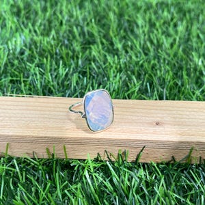 Puede incluir: Un anillo de plata con una gran piedra de &oacute;palo rectangular iridiscente.