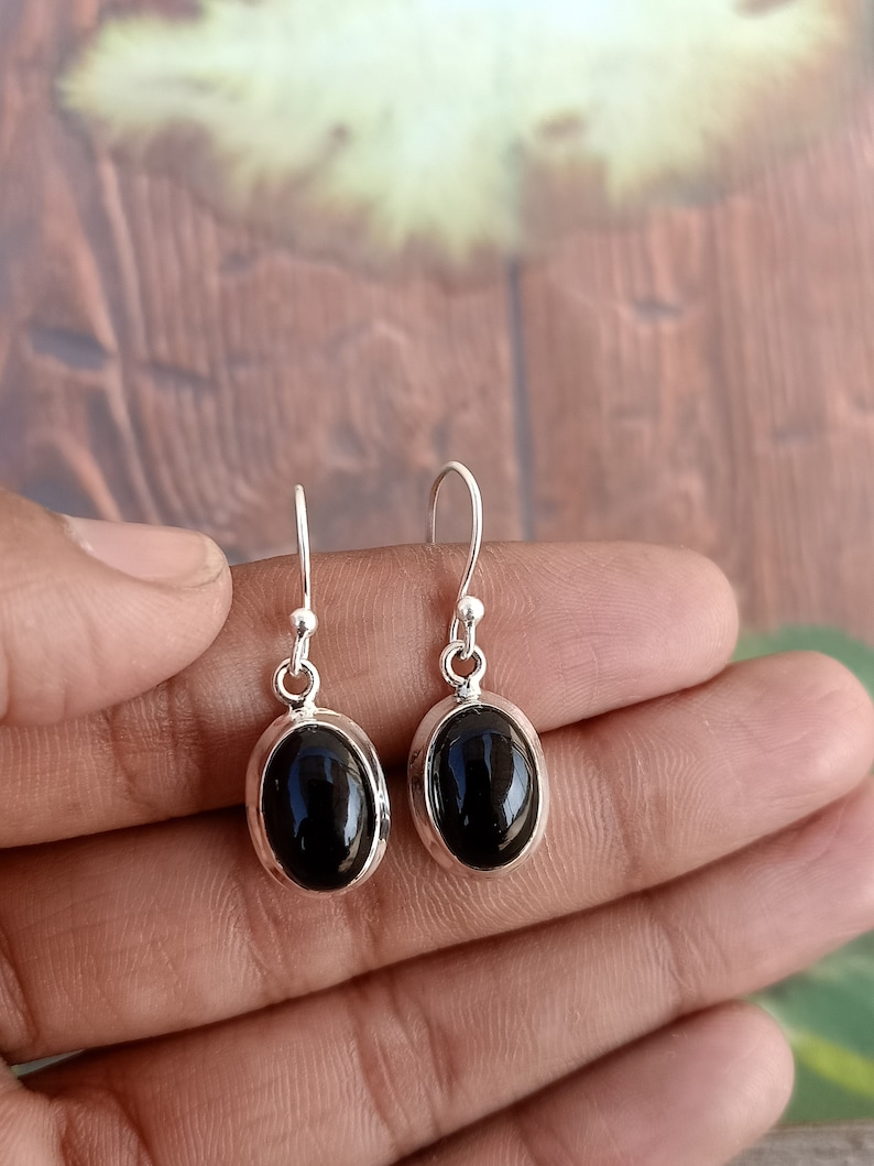 May include: A pair of silver dangle earrings with black oval gemstones.