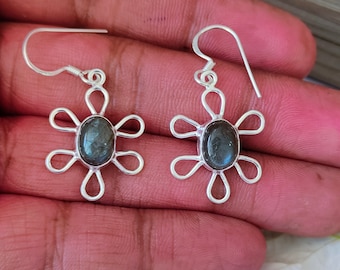 May include: Silver flower-shaped earrings with a dark gray oval gemstone in the center.