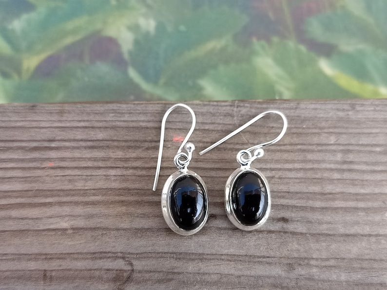 May include: A pair of silver dangle earrings with black oval gemstones.