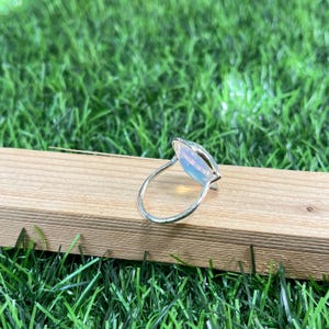 Puede incluir: Un anillo de plata con una gran piedra de &oacute;palo de forma ovalada. El &oacute;palo es iridiscente y tiene un color blanco lechoso.
