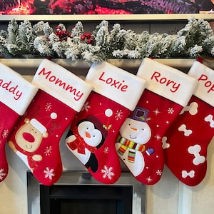 Pode incluir: Cinco meias de Natal vermelhas com punhos brancos, bordadas com os nomes Daddy, Mommy, Loxie, Rory e Poppy. As meias apresentam desenhos aplicados do Pai Natal, uma rena, um pinguim, um boneco de neve e formas de ossos brancos.