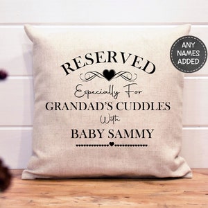 May include: A white pillow with black text that reads "RESERVED Especially For GRANDAD'S CUDDLES With BABY SAMMY". The text is surrounded by decorative flourishes and a heart.