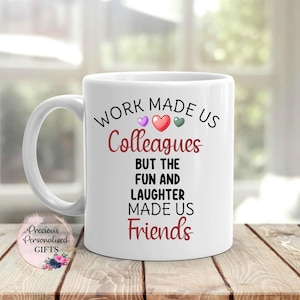 May include: White ceramic mug with a black and red design that reads "Work made us colleagues but the fun and laughter made us friends". There are three small hearts in the design, one purple, one red, and one green.