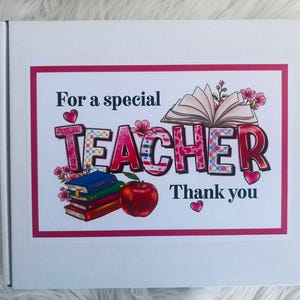 May include: A white box with a pink border featuring the text "For a special TEACHER Thank you." The word TEACHER is in large, colorful letters with floral and book illustrations, and a red apple.