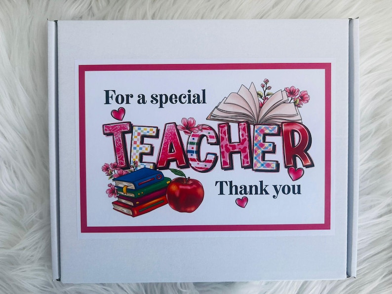 May include: A white box with a pink border featuring the text "For a special TEACHER Thank you." The word TEACHER is in large, colorful letters with floral and book illustrations, and a red apple.