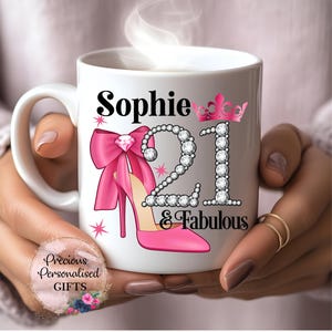 May include: A white ceramic mug with a black handle and the text "But First, Coffee" in a bold, black font. The mug is set against a blurred background, suggesting a cosy setting.