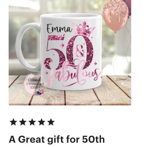 May include: White ceramic mug with a handle, featuring the name "Emma" above a large "50" and the word "fabulous" in pink script. The design includes a crown and glitter accents. A pink balloon is visible in the background.