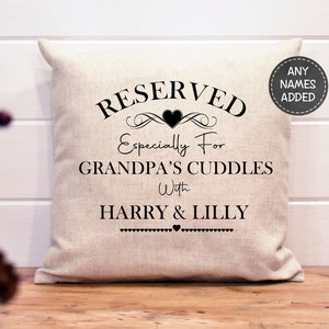 May include: A white linen pillow with black text that reads "RESERVED Especially For GRANDPA'S CUDDLES With HARRY & LILLY" with a small heart between the names.  The text is framed with a decorative flourish and a heart.