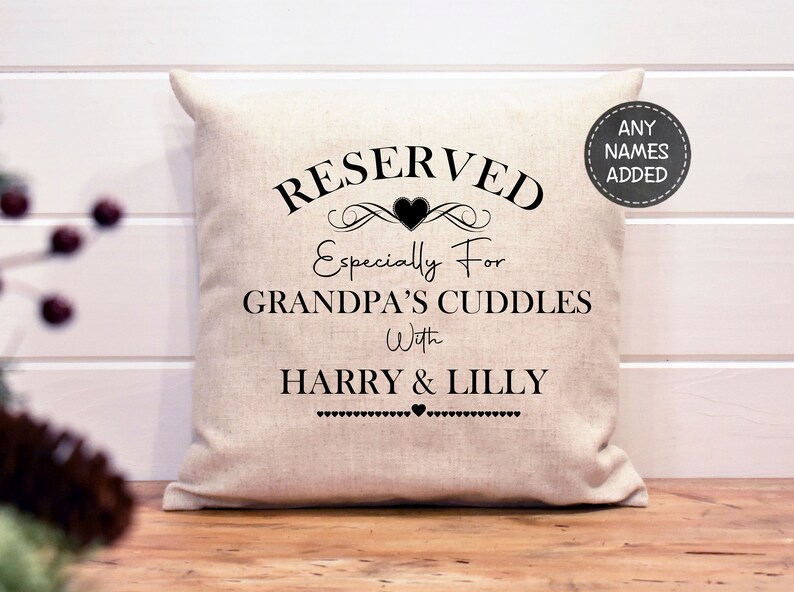 May include: A white linen pillow with black text that reads "RESERVED Especially For GRANDPA'S CUDDLES With HARRY & LILLY" with a small heart between the names.  The text is framed with a decorative flourish and a heart.