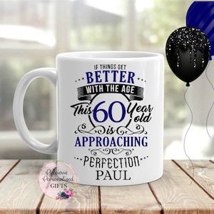 May include: White ceramic mug with a black and blue design. The mug says "If things get better with the age, this 60 year old is approaching perfection." The name Paul is printed below the text.
