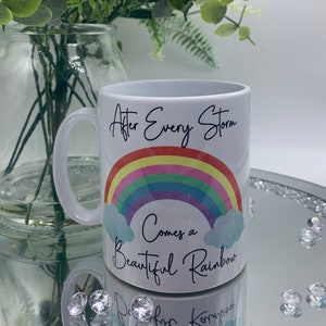 May include: White ceramic mug with a rainbow and the text "After Every Storm Comes a Beautiful Rainbow".