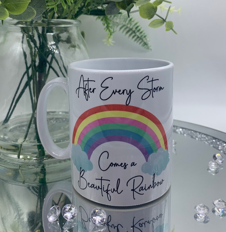 May include: White ceramic mug with a rainbow and the text "After Every Storm Comes a Beautiful Rainbow".