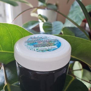 Puede incluir: Un pequeño frasco blanco con tapa negra que contiene un líquido oscuro. La etiqueta del frasco dice "Natural Repellent Mosquito Oil" con las palabras "Made with Essential Oils" y "Aroma Energy" debajo.