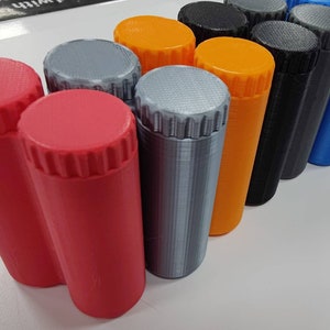 May include: A row of ten small, cylindrical containers with screw-on lids. The containers are in various colors, including red, orange, gray, black, and blue.